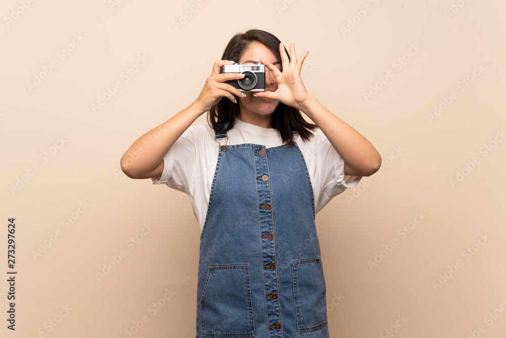 Young Mexican woman over isolated background holding a camera