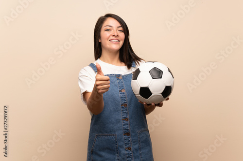 Young Mexican woman over isolated background holding a soccer ball © luismolinero
