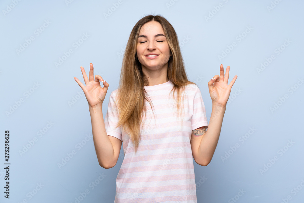Young woman over isolated blue background in zen pose Young woman over isolated blue background in zen pose