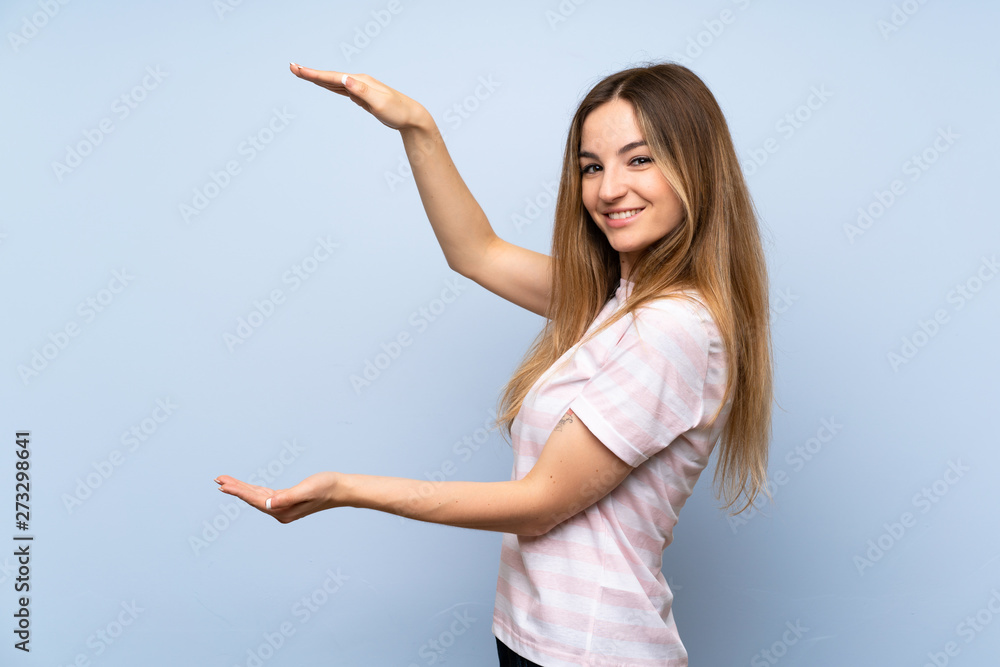 Young woman over isolated blue background holding copyspace to insert an ad Young woman over isolated blue background holding copyspace to insert an ad