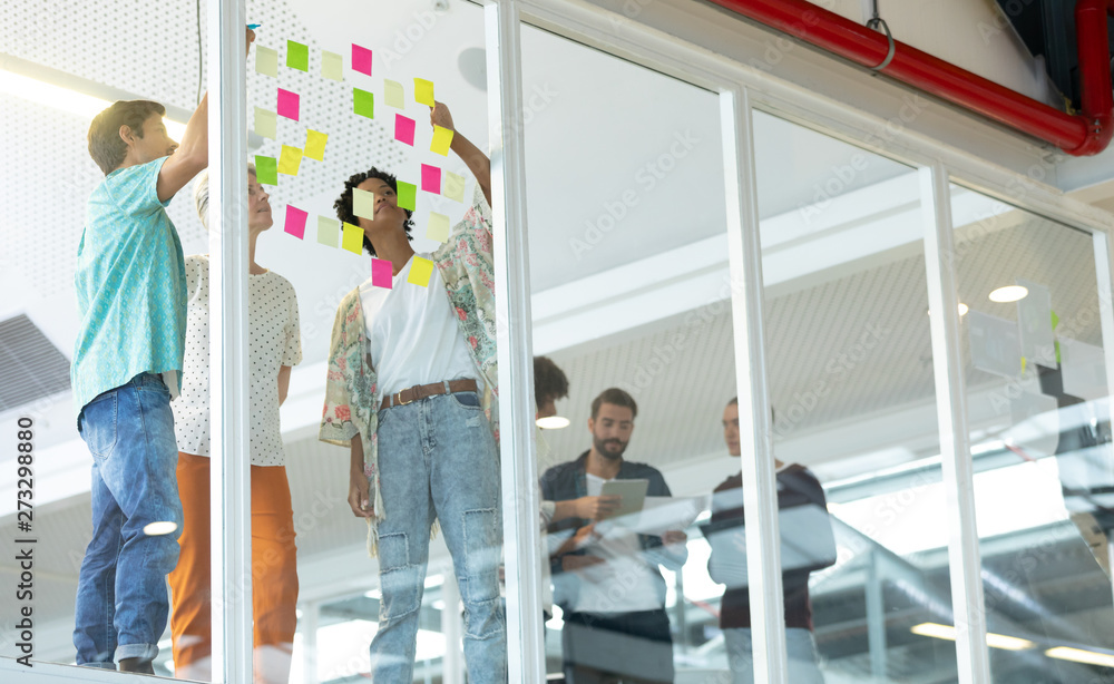 © WavebreakMediaMicro - Business people discussing over sticky notes in the office