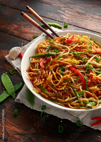 Chow mein, noodles and vegetables dish with wooden chopsticks