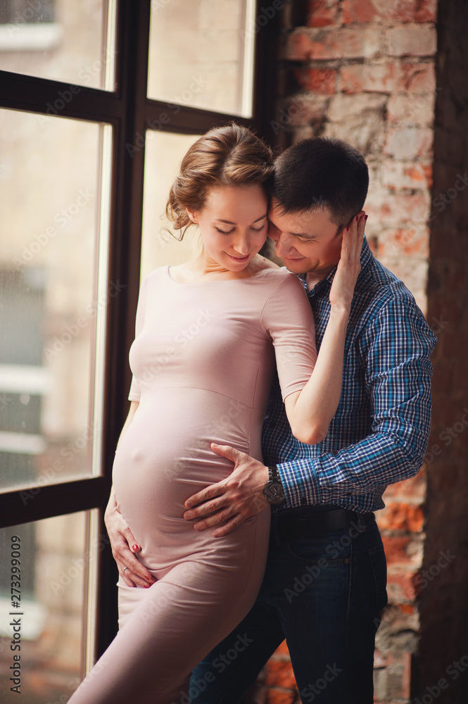 Naklejka premium Cropped image of beautiful pregnant woman and her handsome husband hugging the tummy 