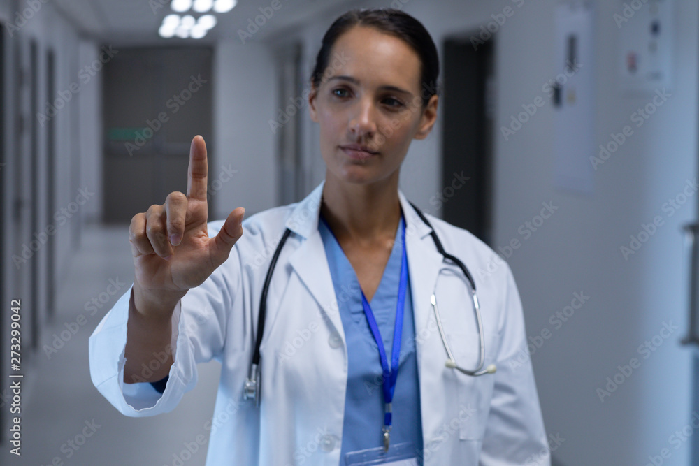 Female doctor pretending to touch an invisible screen in the corridor at hospital Female doctor pretending to touch an invisible screen in the corridor at hospital