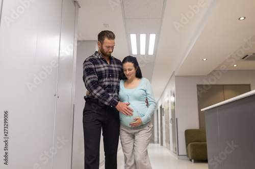 Man comforting pregnant woman while walking in the corridor