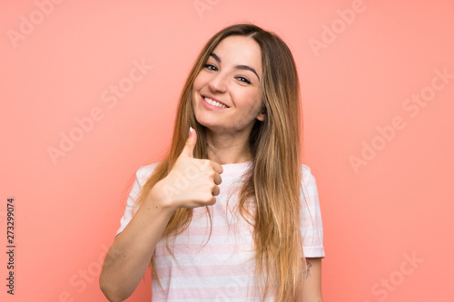 Young woman over isolated pink wall giving a thumbs up gesture