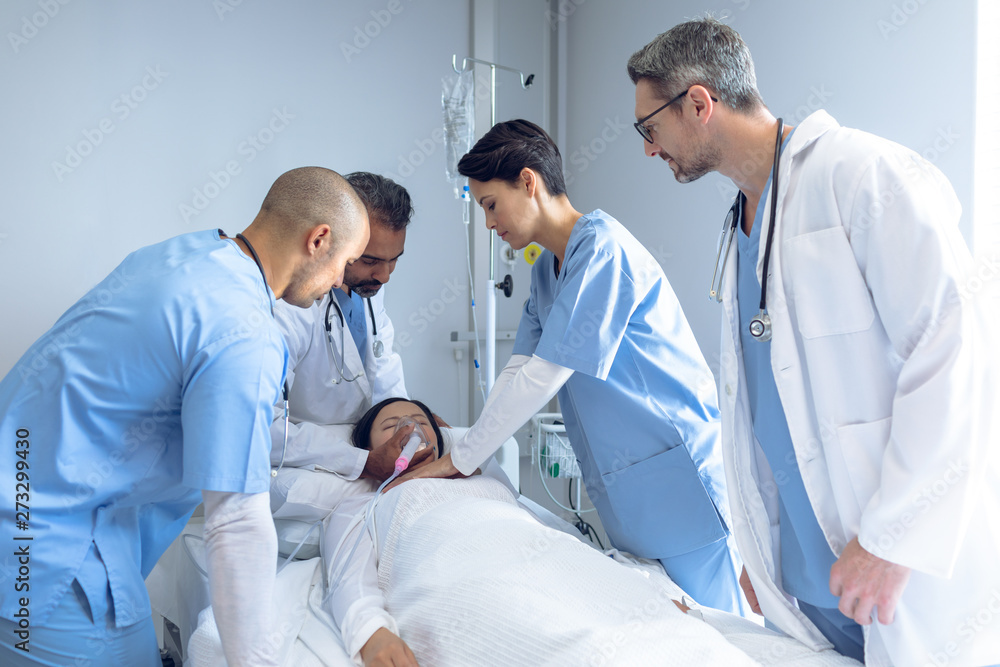 Doctors examining a patient in bed in ward Doctors examining a patient in bed in ward