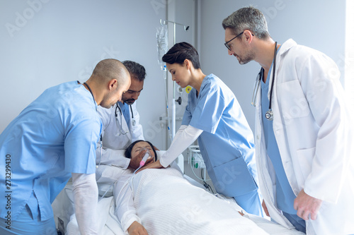 Doctors examining a patient in bed in ward