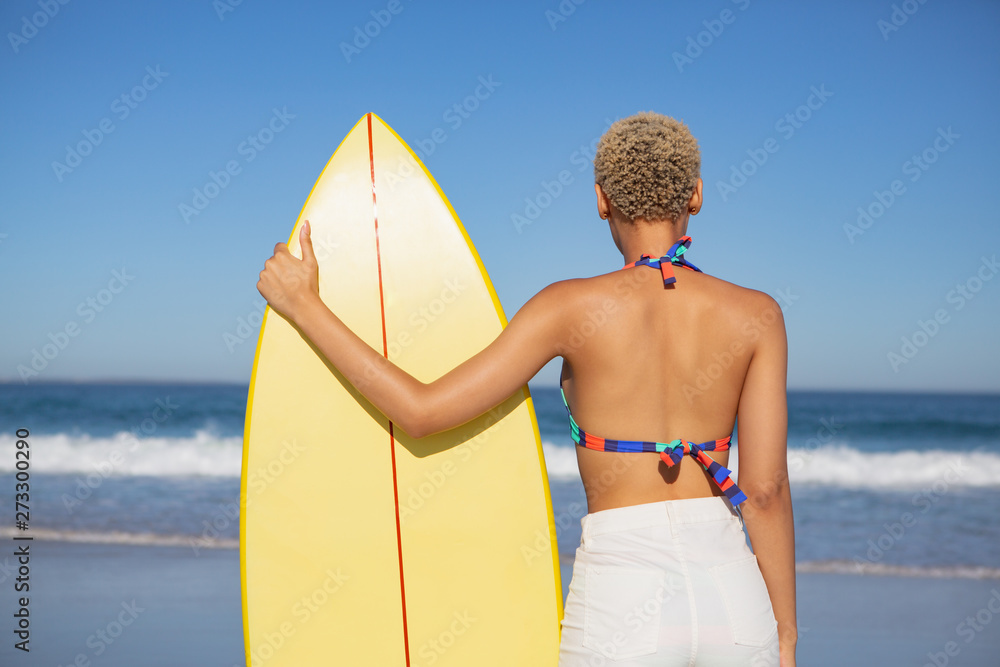 Εκτύπωση καμβά Woman in bikini standing with surfboard on beach in the sunshine