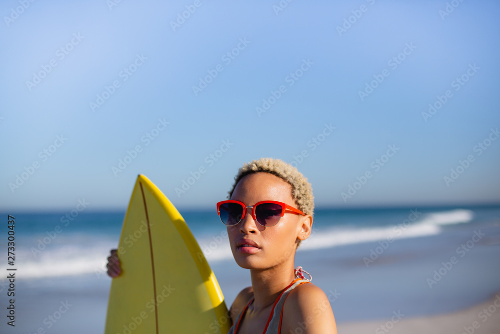 Obraz Woman standing with surfboard at beach in the sunshine fototapeta, plakat