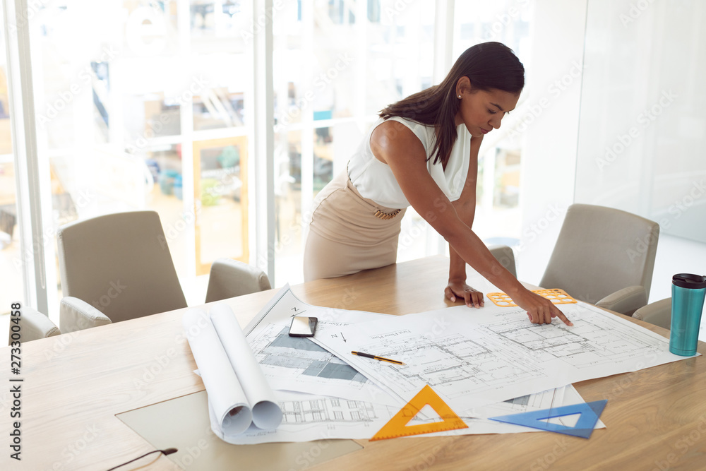 Female architecture working on blueprint on table in a modern office Female architecture working on blueprint on table in a modern office