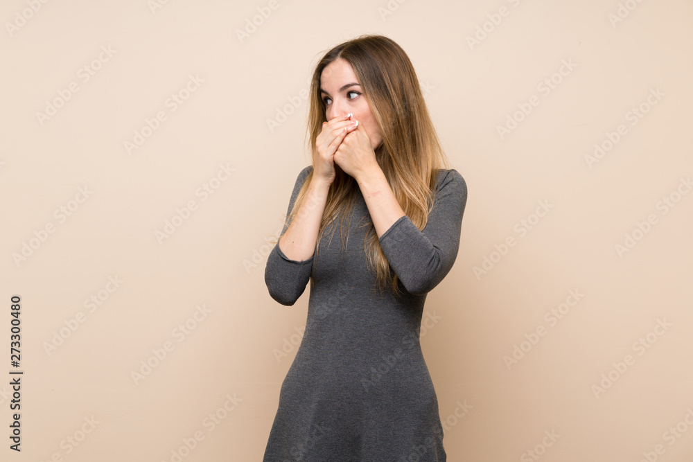 Young woman over isolated background covering mouth and looking to the side Young woman over isolated background covering mouth and looking to the side