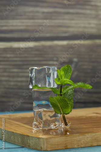 Ice cubes and mint leaves isolated on wooden cutting board