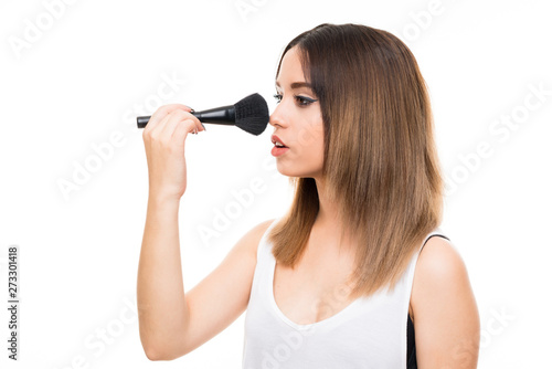 Young woman over isolated white background with makeup brush