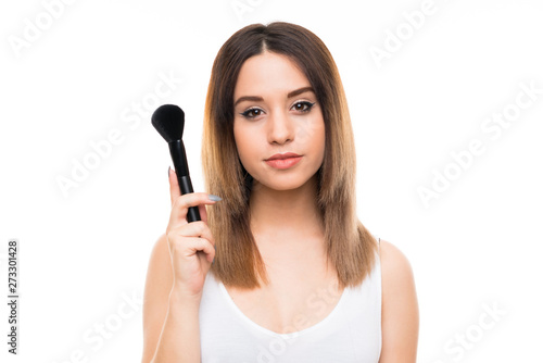 Young woman over isolated white background with makeup brush