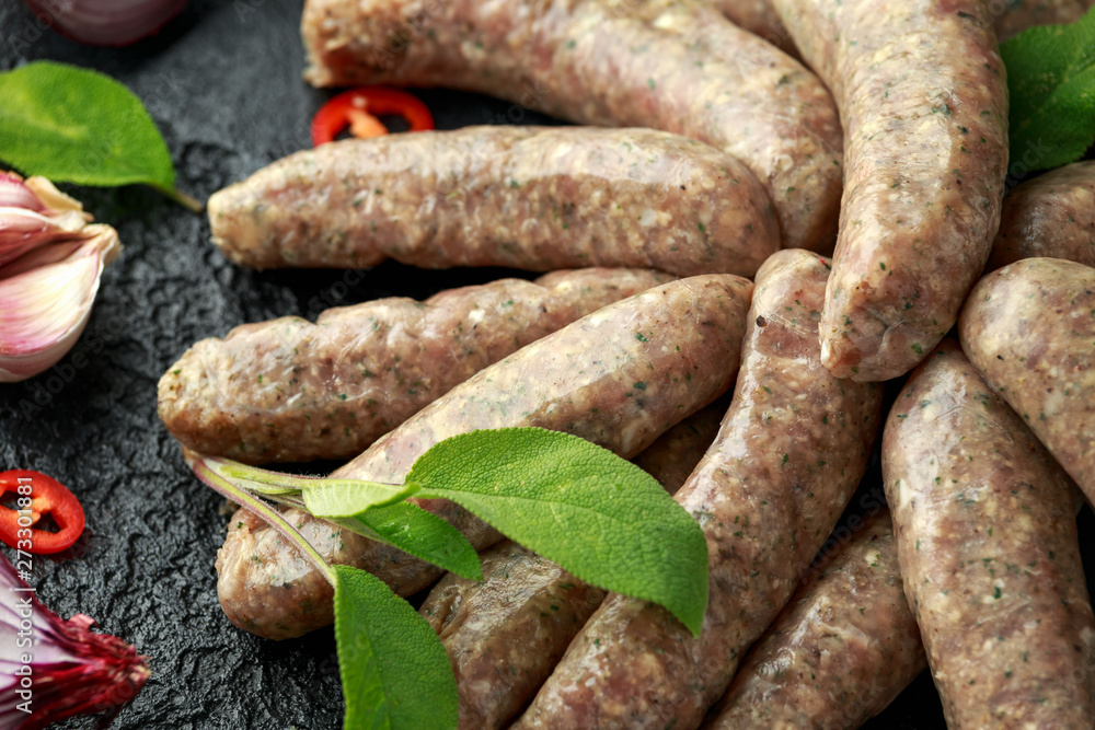 Butcher made sage and onion sausages with chilli on black background Butcher made sage and onion sausages with chilli on black background