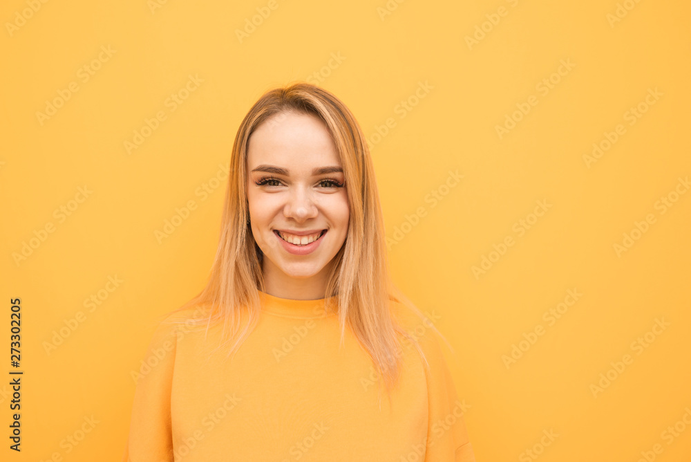 Close-up portrait of a smiling teenage girl on a orange background, wearing a casual clothing, looking into the camera and rejoicing. Positive girl isolated on yellow background. Close-up portrait of a smiling teenage girl on a orange background, wearing a casual clothing, looking into the camera and rejoicing. Positive girl isolated on yellow background.