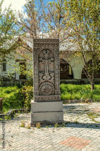 Khachkar of grey stone with ethnic patterns in the courtyard of the Church of the Holy Martyrs in the village of Teghenik in Armenia photo