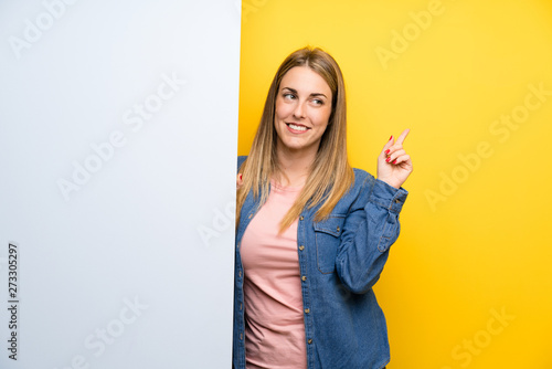 Young woman holding an empty placard pointing with the index finger a great idea