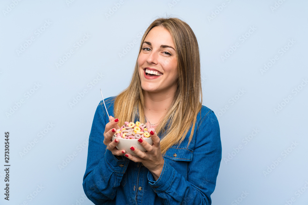 Happy young woman with bowl of cereals over isolated blue wall Happy young woman with bowl of cereals over isolated blue wall