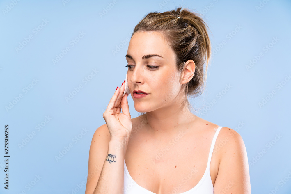 Young blonde woman removing makeup from her face with cotton pad Young blonde woman removing makeup from her face with cotton pad