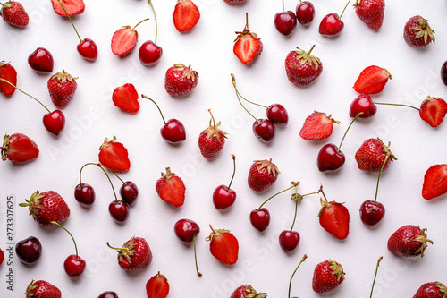 Creative berry layout made of seasonal summer fruits. Healthy food concept. Cherries and fresh juicy strawberries texture on white background