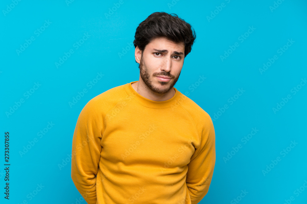 Handsome over isolated blue wall with sad and depressed expression Handsome over isolated blue wall with sad and depressed expression