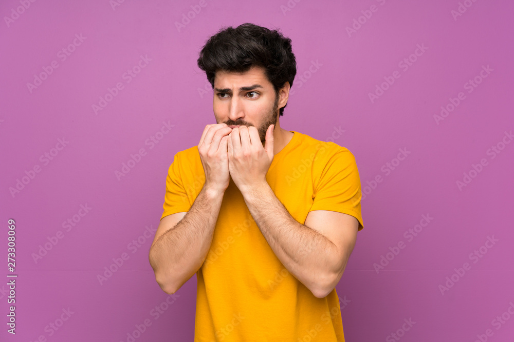 Handsome over isolated purple wall nervous and scared putting hands to mouth Handsome over isolated purple wall nervous and scared putting hands to mouth