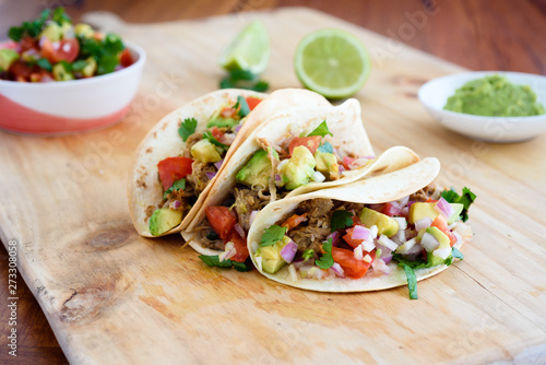 Pulled pork tacos with salsa, guacamole and lime in background, with copy space photo