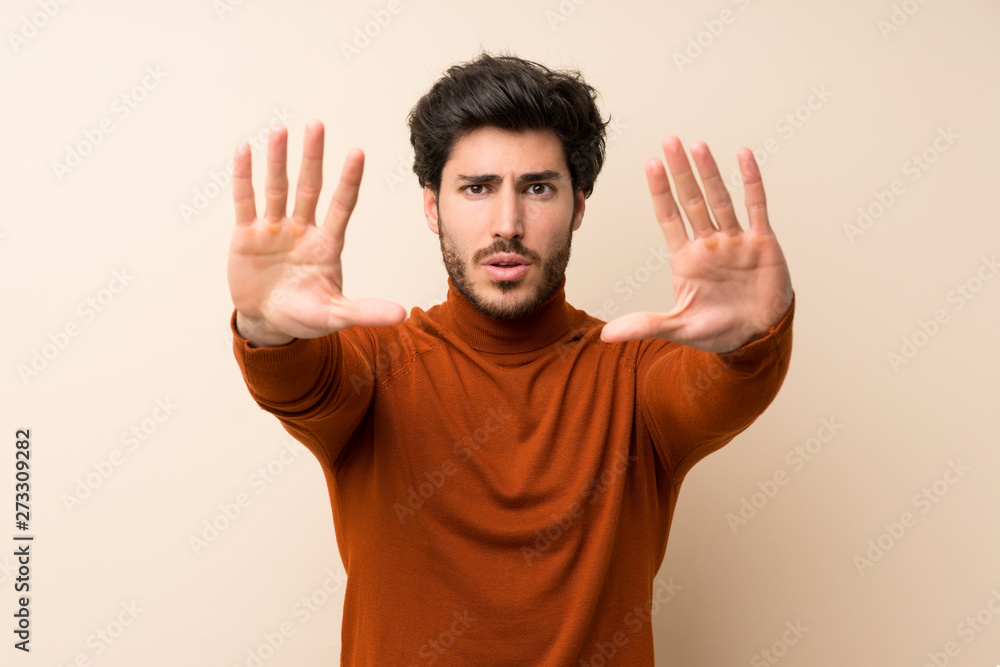 Handsome over isolated wall making stop gesture and disappointed Handsome over isolated wall making stop gesture and disappointed