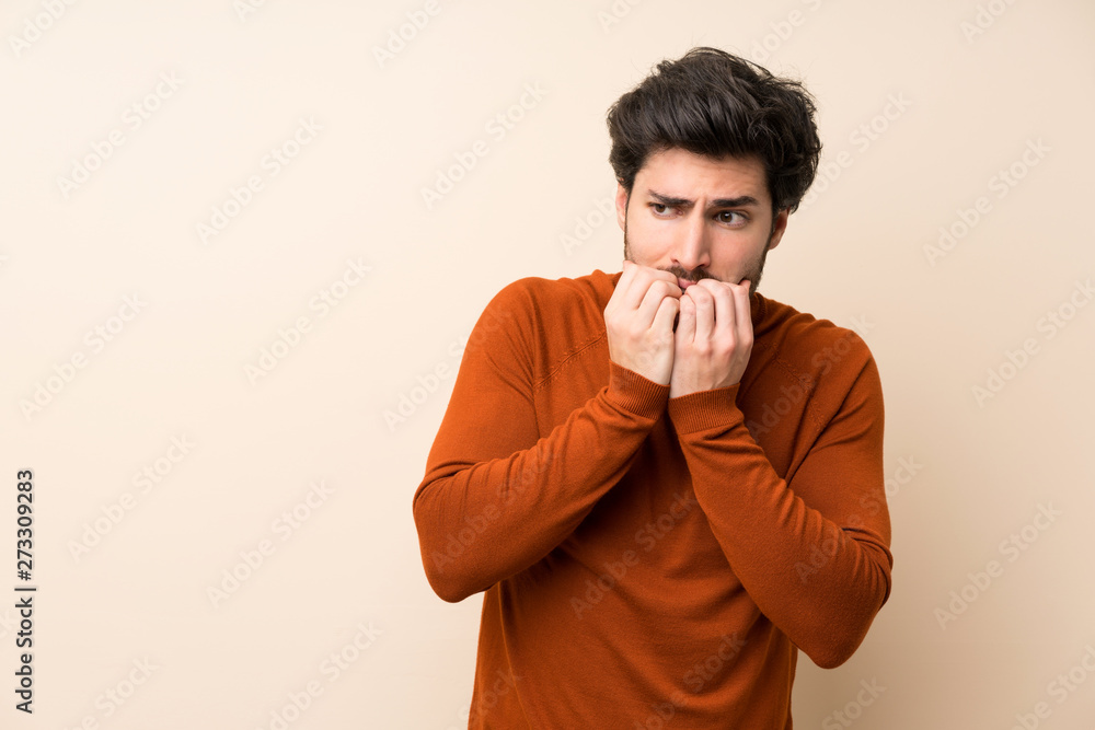 Handsome over isolated wall nervous and scared putting hands to mouth Handsome over isolated wall nervous and scared putting hands to mouth