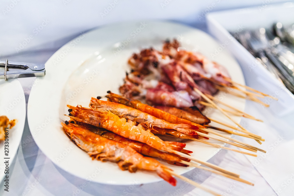 Grilled butter shrimps skewer in stick and Squid Sticks on White Plate. Grilled butter shrimps skewer in stick and Squid Sticks on White Plate.