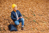 Stylish cute boy on a walk with phone. Technology, social media, kids lifestyle. Autumn fashion and kids trends. Autumn mood. Happy school boy in autumn park