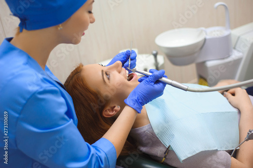 Doctor in uniform checking up female patient s teeth in dental clinic
