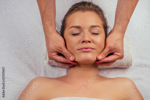 Young woman enjoys ayurvedic facial massage in luxury resort dark lighting