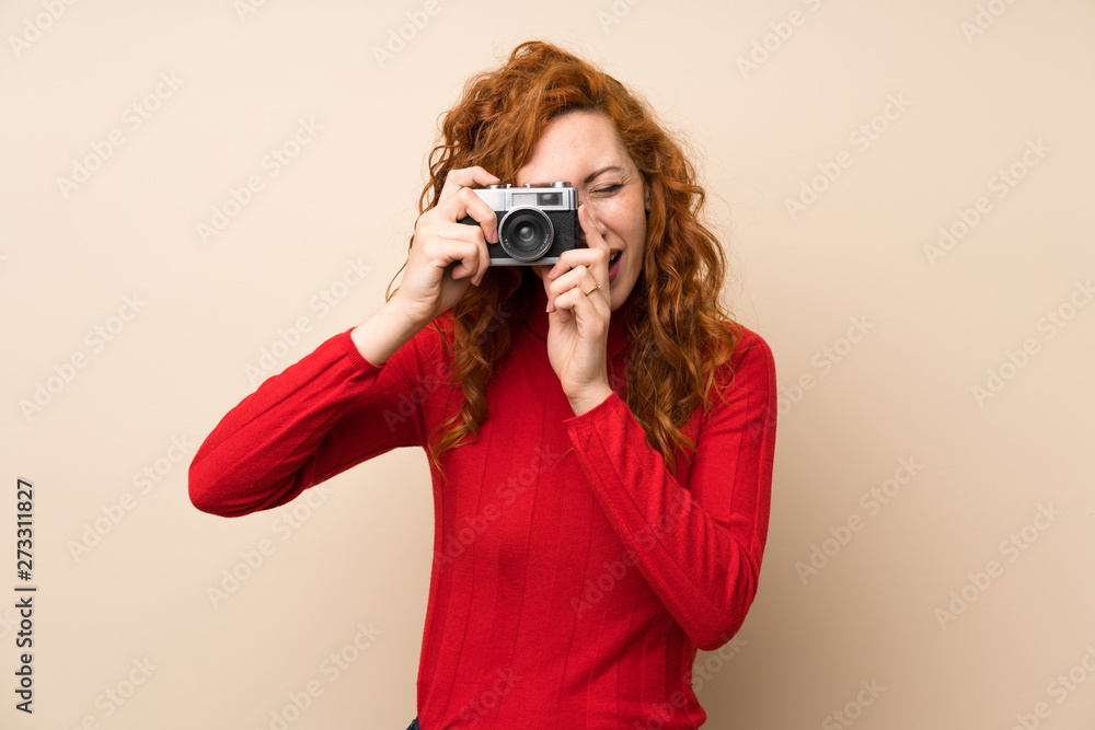 Redhead woman with turtleneck sweater holding a camera Redhead woman with turtleneck sweater holding a camera