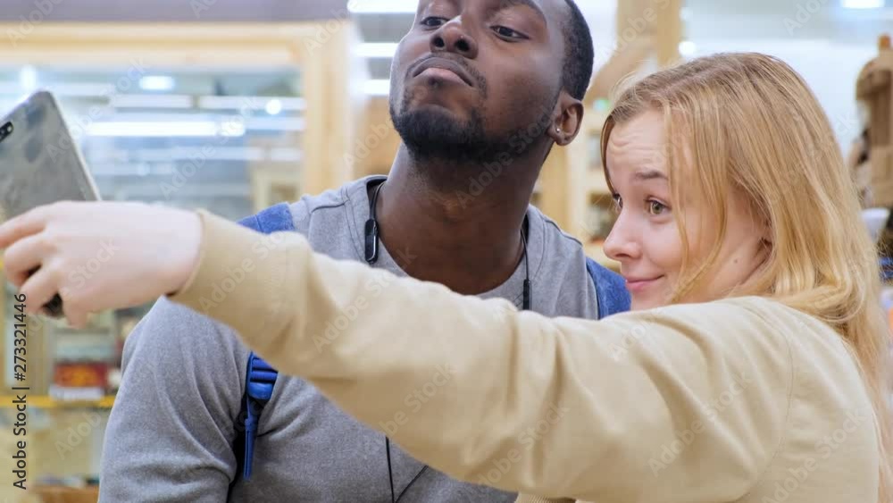 Man and woman in shopping mall. Couple is taking selfie with selfie stick. Couple is smiling Man and woman in shopping mall. Couple is taking selfie with selfie stick. Couple is smiling