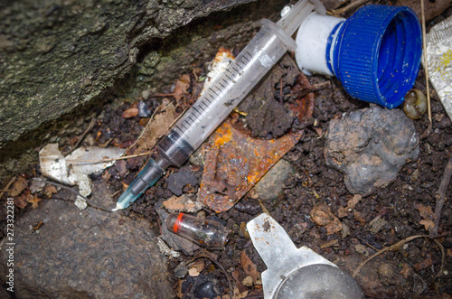 Obraz na plátně Close-up of syringe and other debris discarded by drug users on patch of waste g