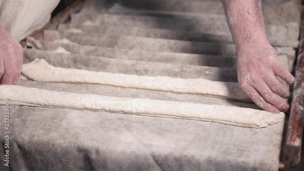 Baker preparing rows of uncooked dough loaf in bakery production to next phase of baking . Baker preparing rows of uncooked dough loaf in bakery production to next phase of baking .