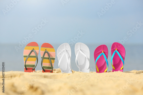 Different bright flip flops in sand. Beach accessories