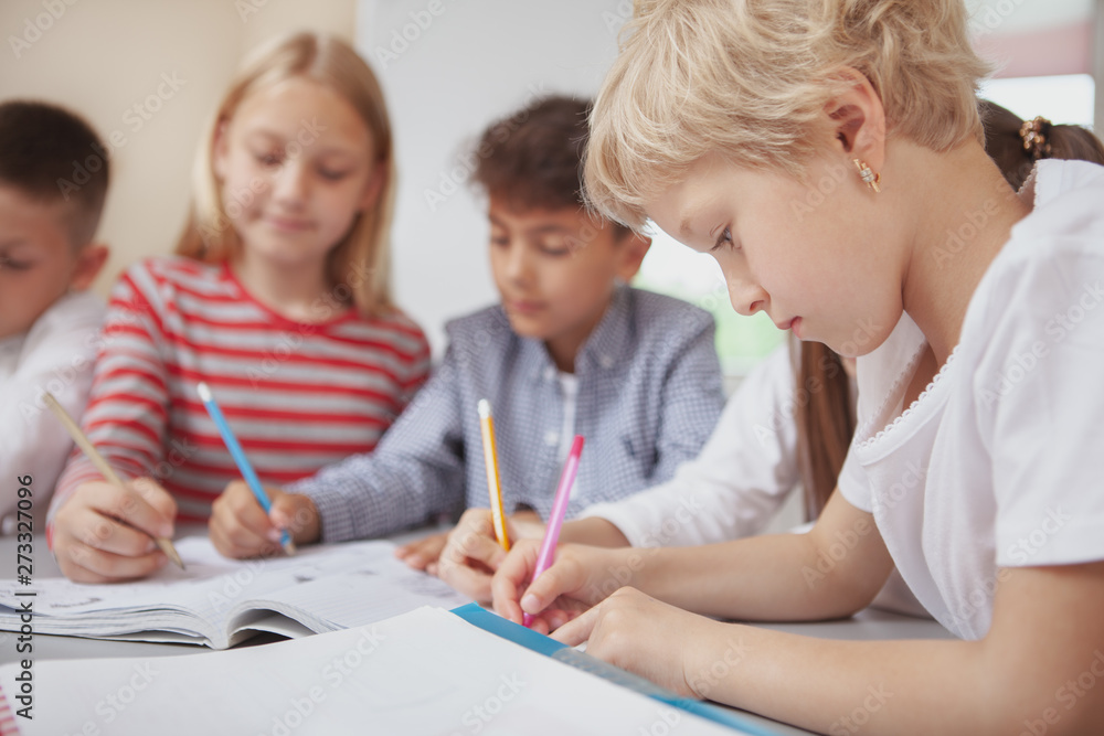Happy little kids concentrating, drawing at art class together. Lovely schoolchildren working on a creative art project together, sketching with colorful pencils Happy little kids concentrating, drawing at art class together. Lovely schoolchildren working on a creative art project together, sketching with colorful pencils