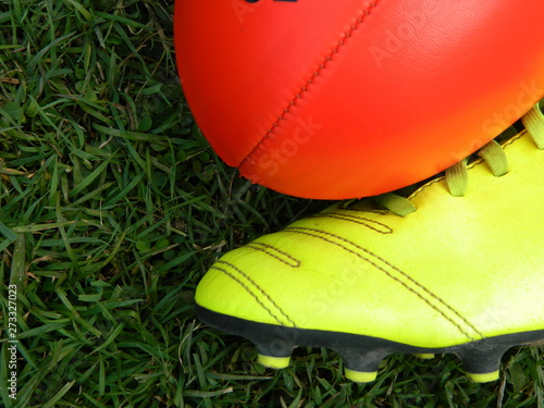 Red football and football boot on a grass background