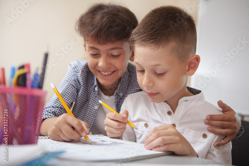 Friendship, childhood, leisure activities concept. Close up of two adorable young boys enjoying drawing together. Lovely schoolboys doing art class assignment photo