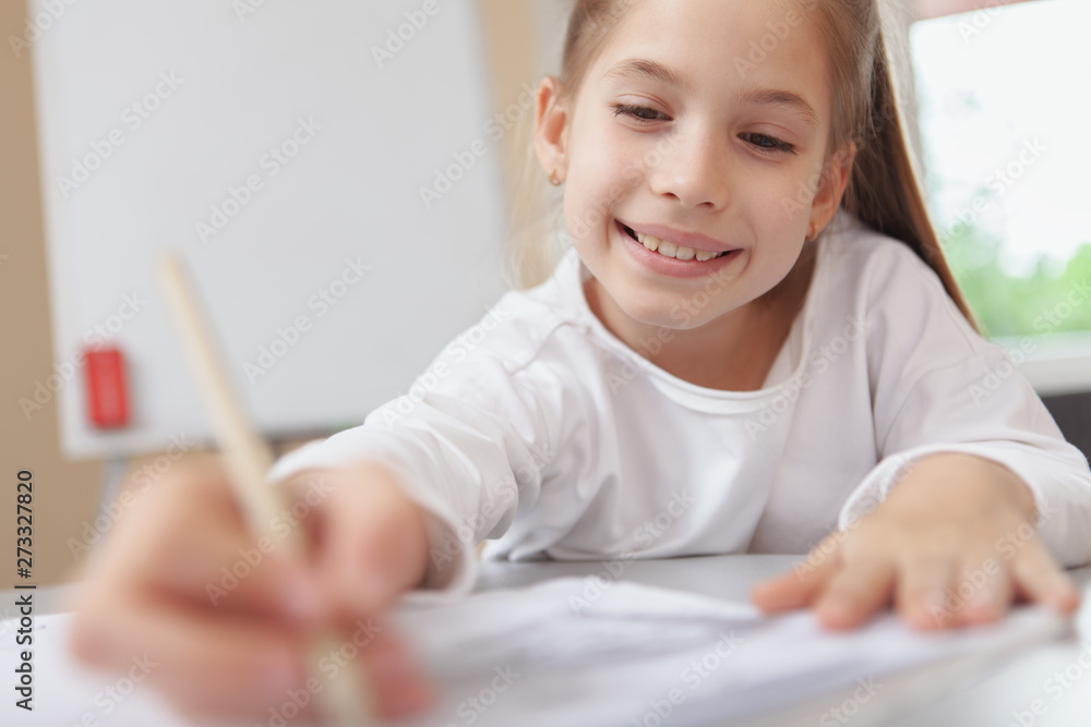 Cropped shot of a lovely happy young girl concentrating, drawing or writing in her textbook, copy space. Children education, development concept Cropped shot of a lovely happy young girl concentrating, drawing or writing in her textbook, copy space. Children education, development concept