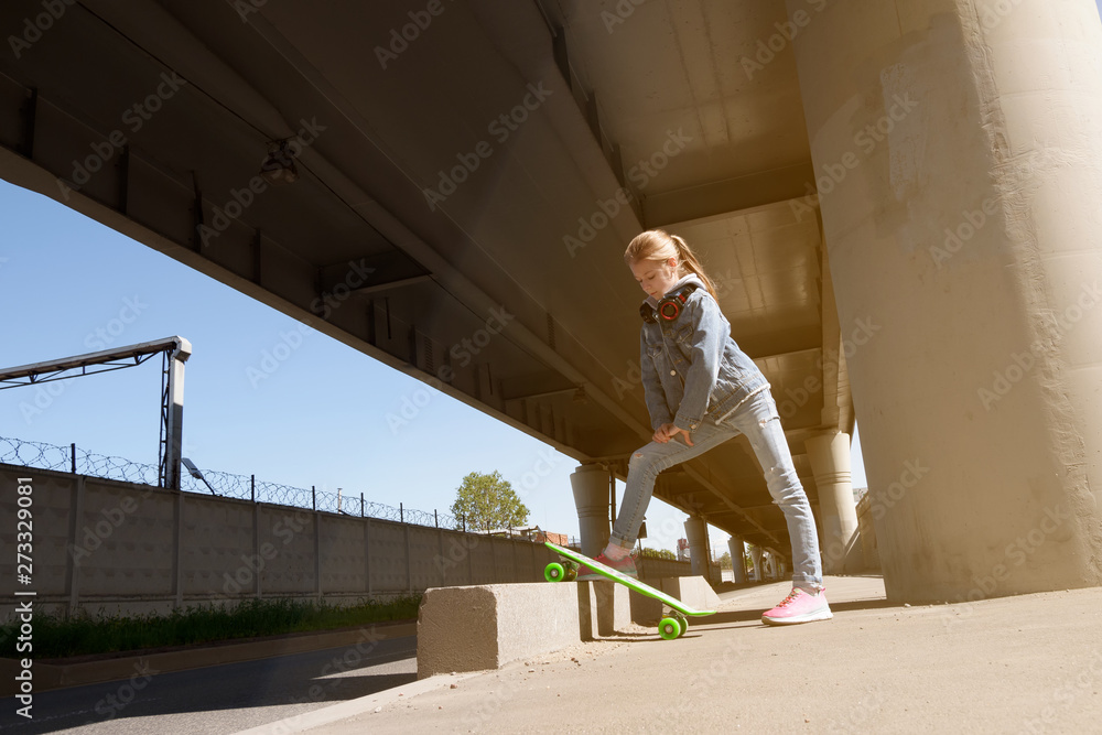 Teen on skateboard in jeans clothes, on the background of industrial	