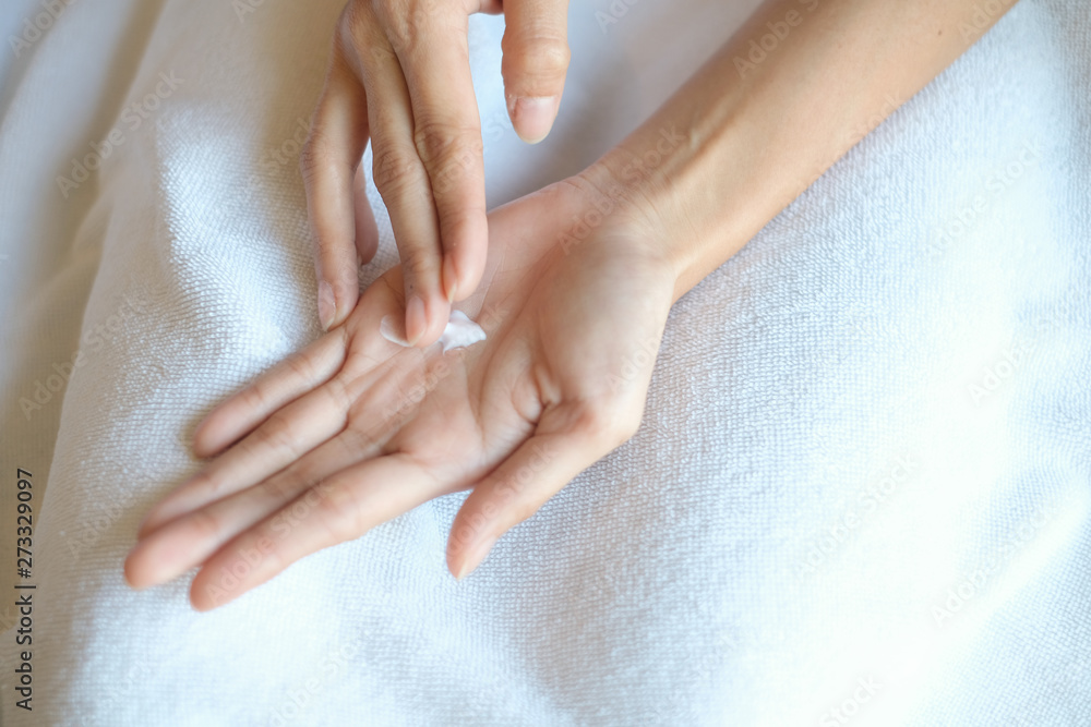 Naklejka premium Woman applying moisturizing cream/lotion on hands, beauty concept.