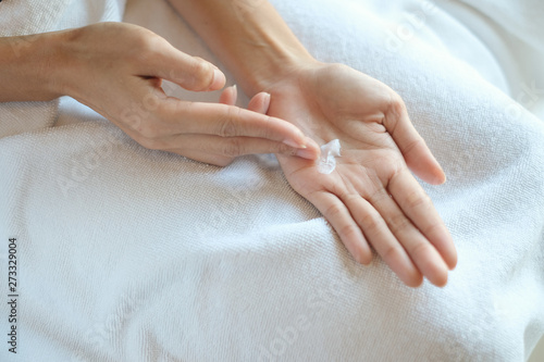 Woman applying moisturizing cream lotion on hands  beauty concept.