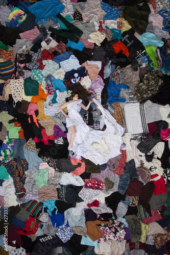 model surrounded by clothes, unsustainable fashion