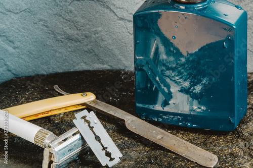 Tableau sur toile Blue aftershave bottle with old razor on wet stone texture