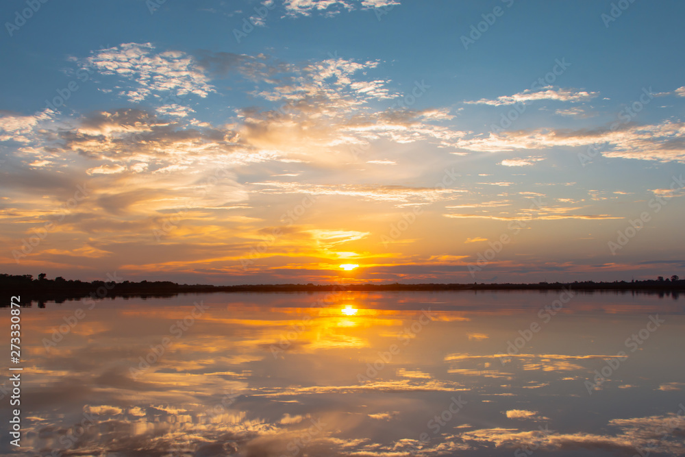 Fototapeta premium Sunset reflection lagoon. beautiful sunset behind the clouds and blue sky above the over lagoon landscape background. dramatic sky with cloud at sunset